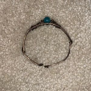 bronze colored bracelet with teal stone on top